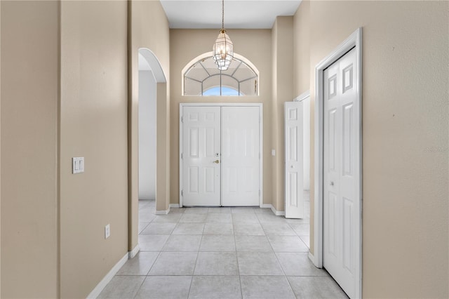 entryway with light tile patterned floors, an inviting chandelier, and a high ceiling