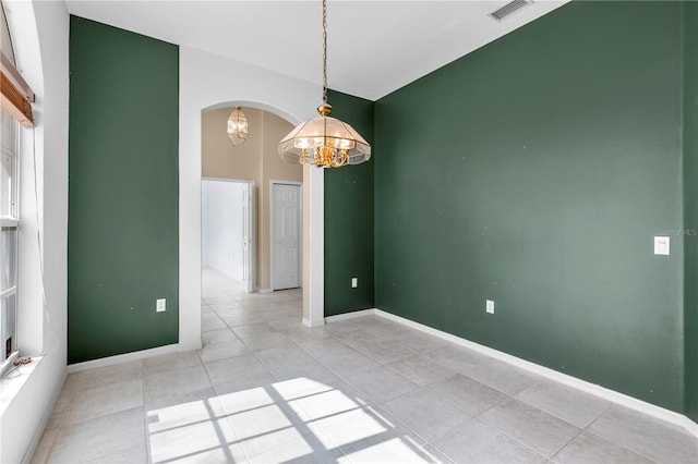 tiled spare room with a notable chandelier