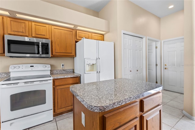 kitchen featuring a kitchen island, light tile patterned flooring, and white appliances