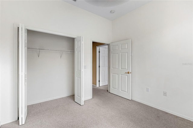 unfurnished bedroom featuring light carpet and a closet