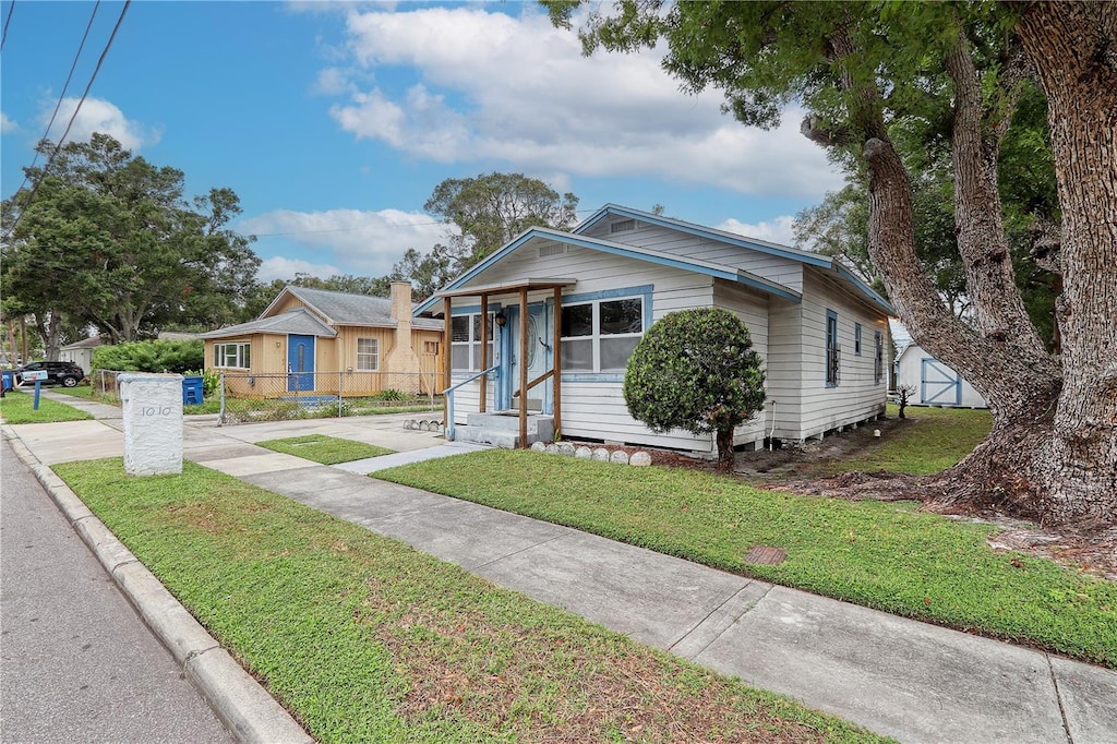 bungalow-style home with a front lawn and a storage unit