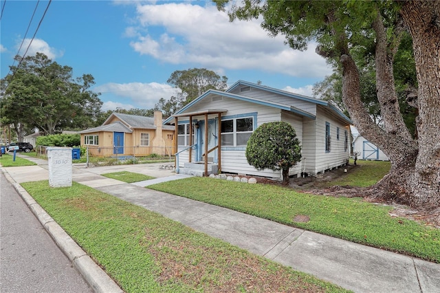 bungalow-style home with a front lawn and a storage unit