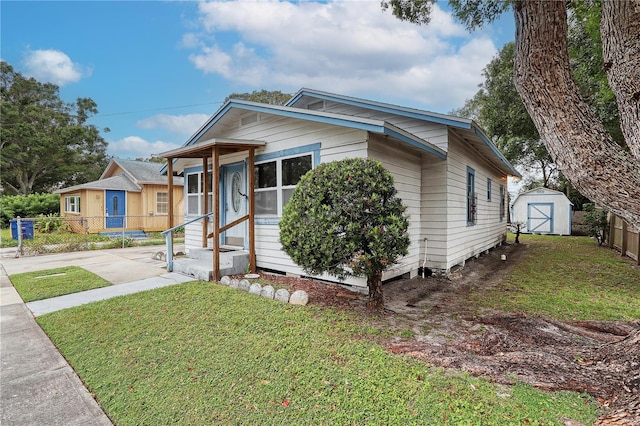 bungalow-style home with a front lawn and a storage unit