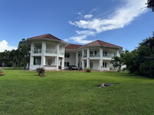 rear view of house with a lawn and a balcony