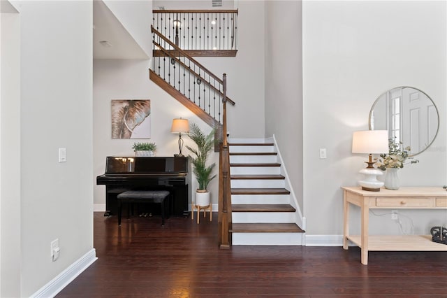 staircase with a towering ceiling and wood-type flooring