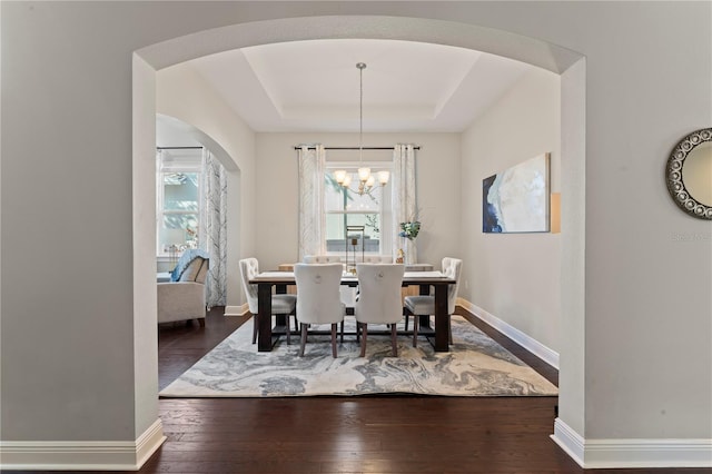 dining area with a tray ceiling, dark hardwood / wood-style flooring, and a chandelier