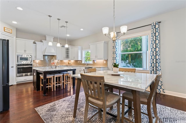 dining space with dark hardwood / wood-style flooring, a notable chandelier, and sink