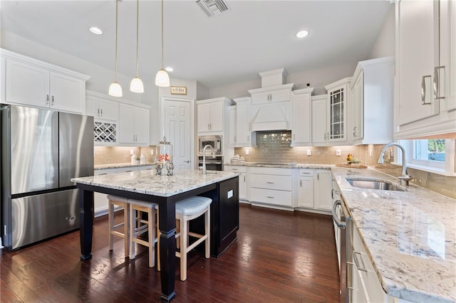 kitchen featuring white cabinetry, sink, a center island, pendant lighting, and appliances with stainless steel finishes