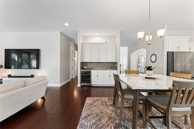 dining area featuring an inviting chandelier, dark hardwood / wood-style floors, wine cooler, and sink