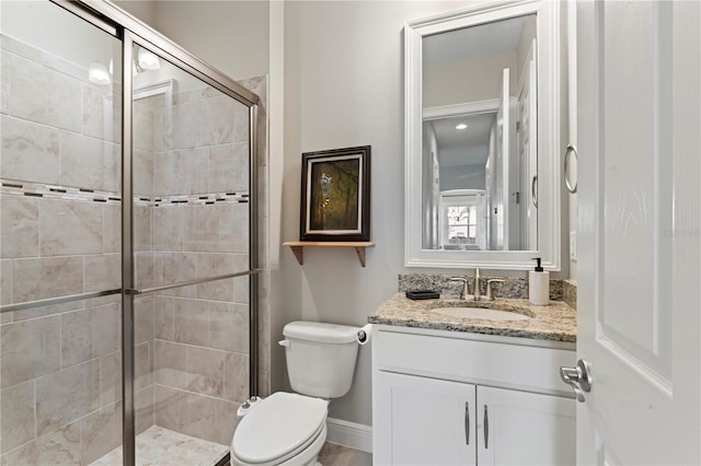 bathroom featuring vanity, toilet, and a shower with door