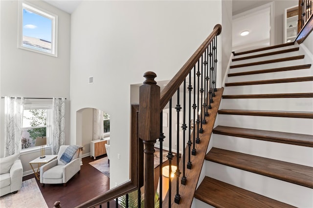 stairway with plenty of natural light and wood-type flooring