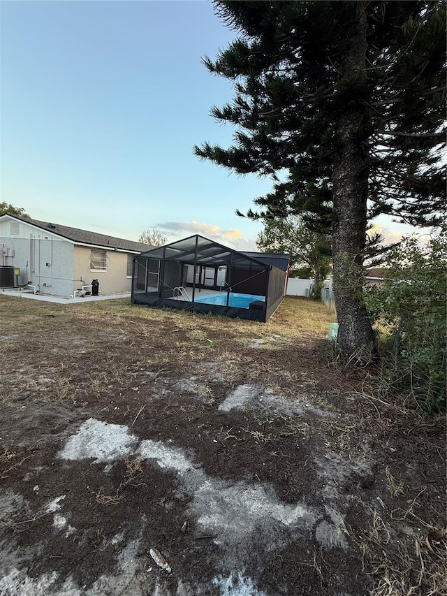 view of yard with central AC unit and a lanai