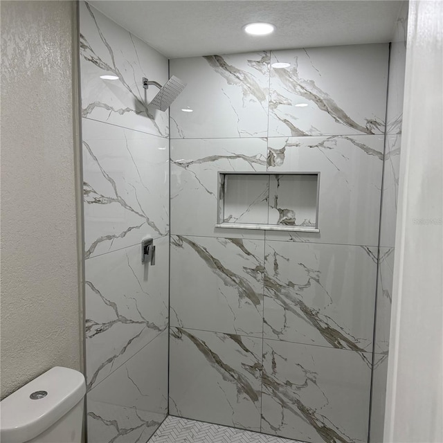 bathroom featuring a tile shower and toilet