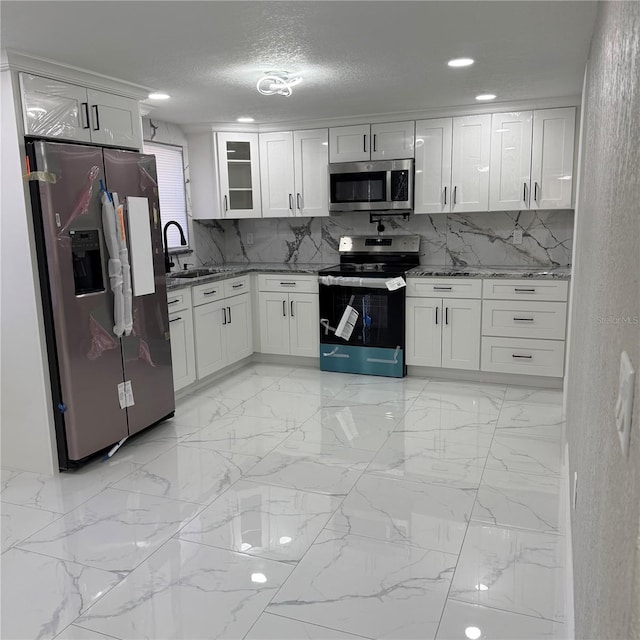 kitchen with white cabinets, light stone counters, sink, and appliances with stainless steel finishes