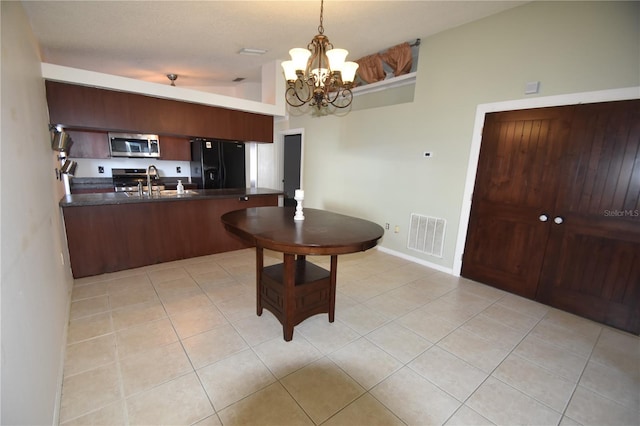 kitchen featuring hanging light fixtures, black refrigerator with ice dispenser, a notable chandelier, kitchen peninsula, and light tile patterned flooring