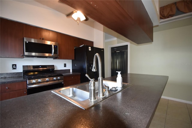 kitchen with sink, stainless steel appliances, and dark tile patterned flooring