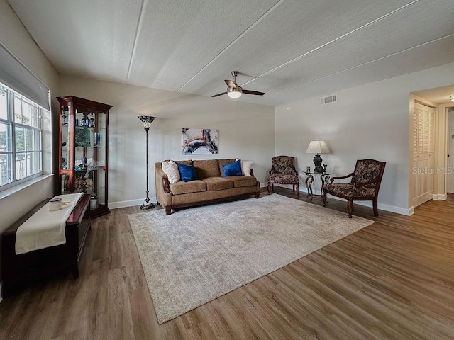 living room featuring dark hardwood / wood-style flooring, a textured ceiling, and ceiling fan