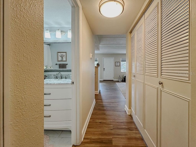 hall featuring hardwood / wood-style floors, a textured ceiling, and sink