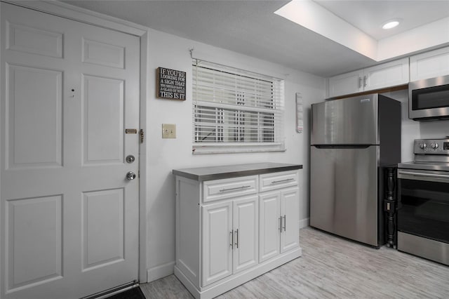 kitchen with white cabinets, appliances with stainless steel finishes, and light wood-type flooring