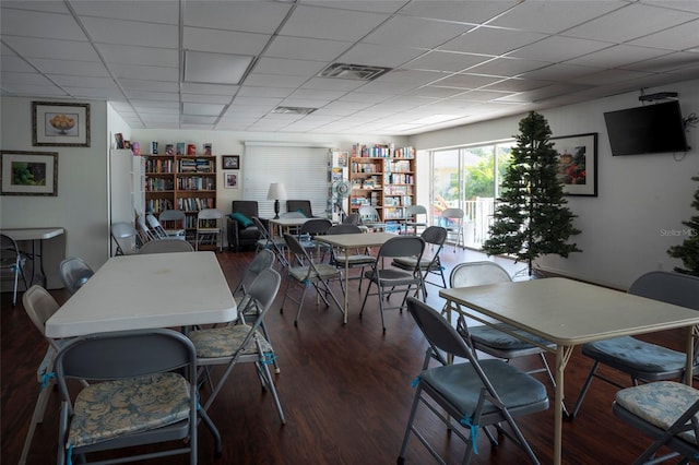 dining area with a drop ceiling and dark hardwood / wood-style flooring