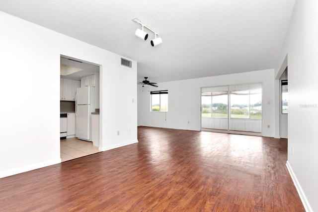 unfurnished living room featuring a textured ceiling, light wood-type flooring, and ceiling fan