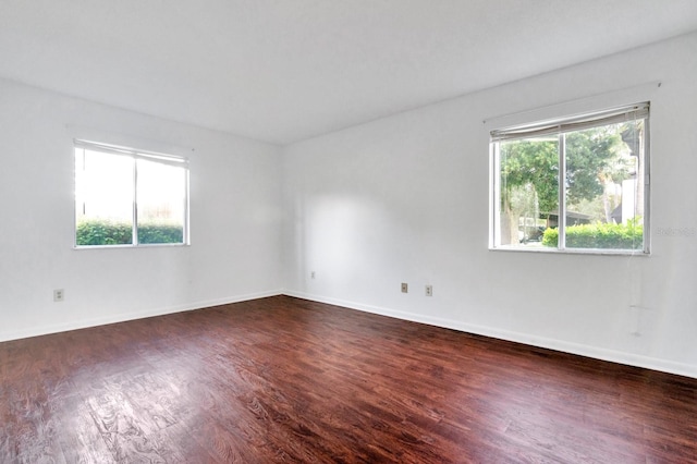 unfurnished room featuring dark wood-type flooring and a healthy amount of sunlight