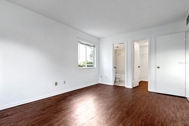 unfurnished bedroom featuring dark hardwood / wood-style flooring, connected bathroom, a closet, and a walk in closet