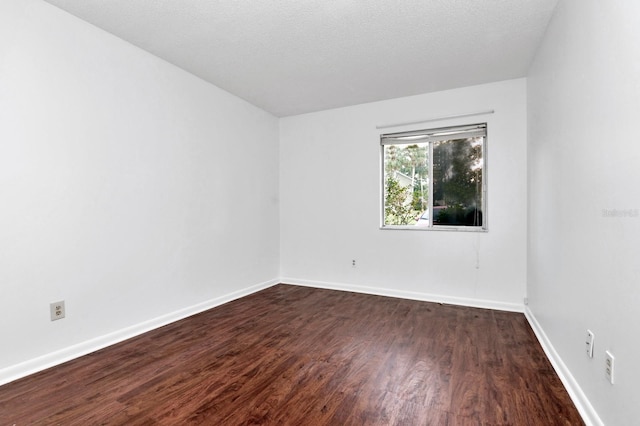 spare room with dark wood-type flooring and a textured ceiling