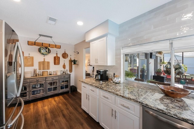 kitchen featuring dark wood-type flooring, white cabinets, decorative backsplash, and stainless steel appliances