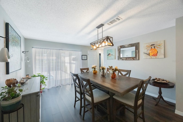 dining room featuring dark wood-type flooring and a textured ceiling