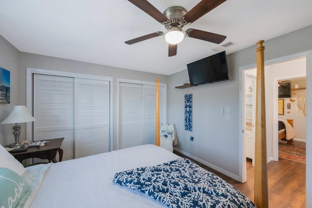 bedroom with hardwood / wood-style floors, two closets, and ceiling fan