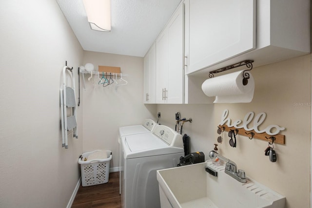 laundry room featuring separate washer and dryer, a textured ceiling, cabinets, sink, and dark wood-type flooring