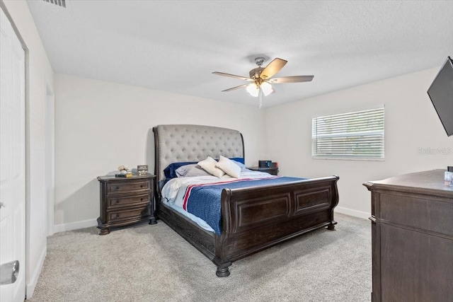 bedroom featuring a textured ceiling, light carpet, and ceiling fan