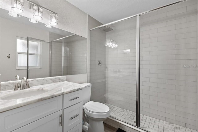 bathroom with toilet, an enclosed shower, vanity, and a textured ceiling