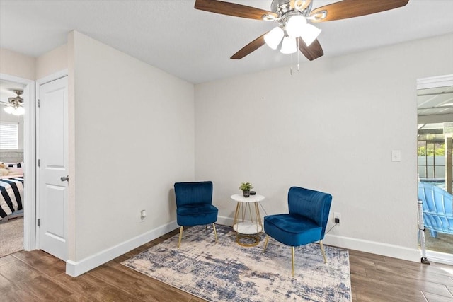 living area featuring dark hardwood / wood-style flooring and ceiling fan