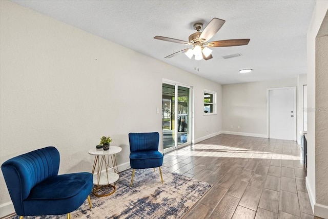 sitting room featuring a textured ceiling, hardwood / wood-style floors, and ceiling fan