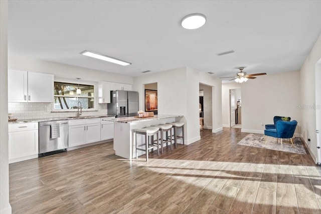 kitchen featuring sink, appliances with stainless steel finishes, a kitchen bar, light hardwood / wood-style flooring, and white cabinets