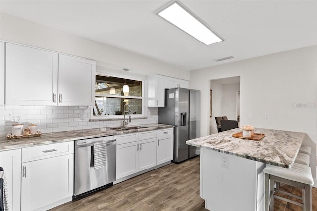 kitchen with stainless steel appliances, a breakfast bar area, white cabinets, and sink