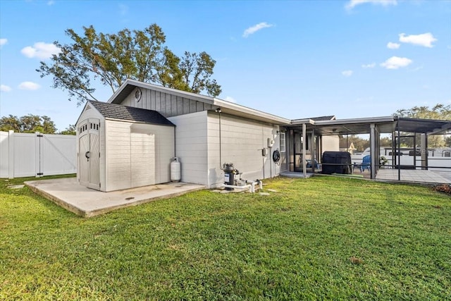 back of house featuring a patio area, a yard, and a storage shed