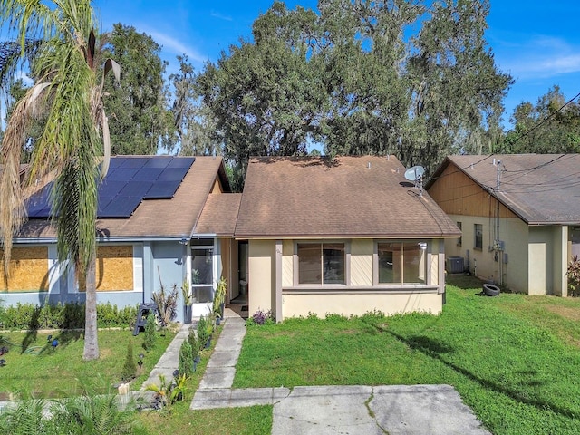 view of front of property featuring solar panels, central air condition unit, and a front lawn