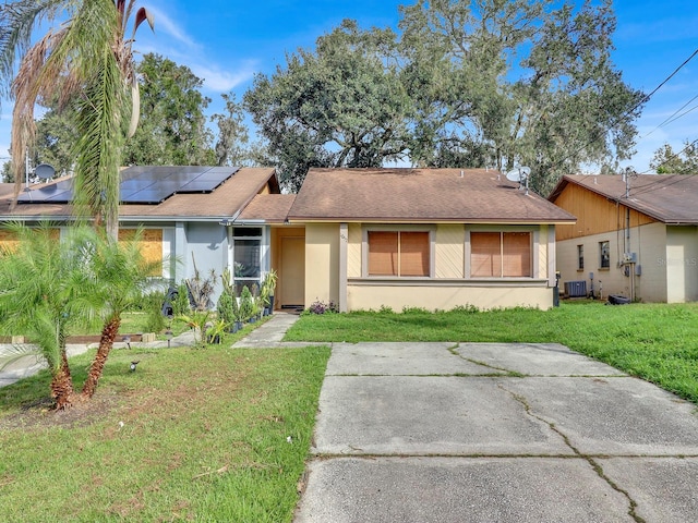 single story home featuring solar panels, cooling unit, and a front yard