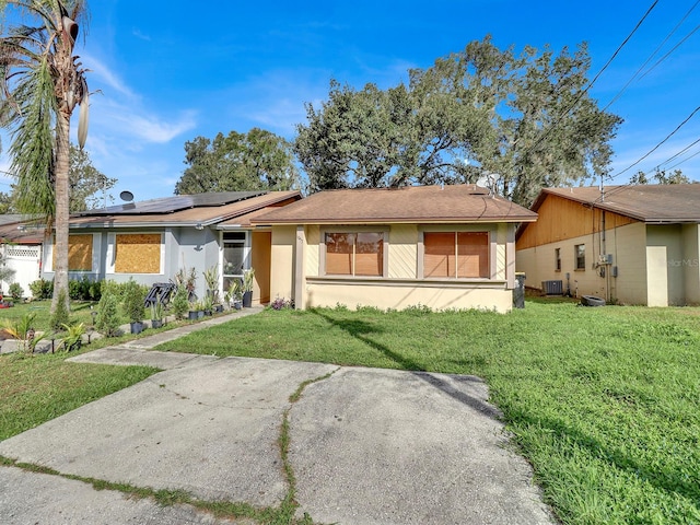 ranch-style house featuring central AC unit, solar panels, and a front yard