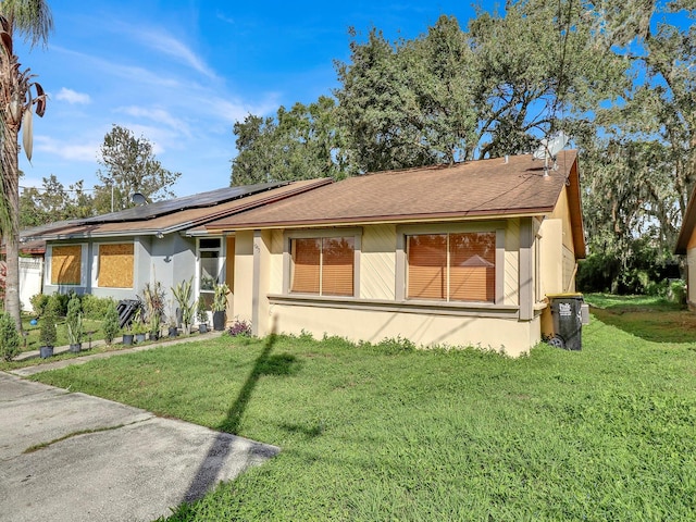 ranch-style house featuring solar panels and a front lawn