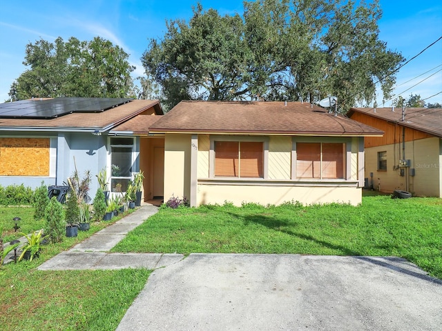 ranch-style home with a front lawn and solar panels