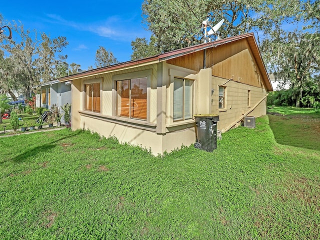 view of side of property with a lawn and central AC