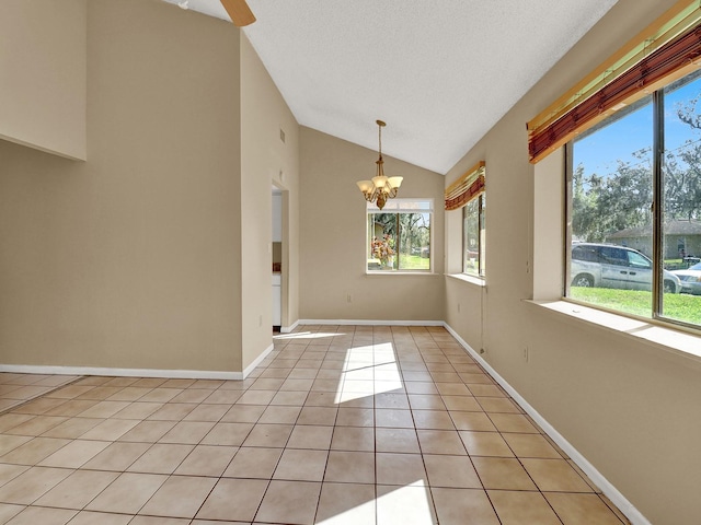 spare room with ceiling fan with notable chandelier, a healthy amount of sunlight, light tile patterned flooring, and a textured ceiling