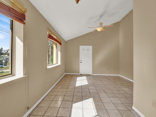 empty room with plenty of natural light, light tile patterned flooring, and lofted ceiling