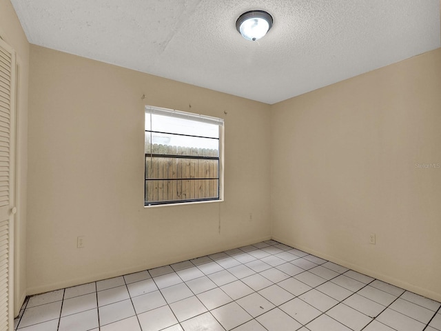 tiled empty room with a textured ceiling