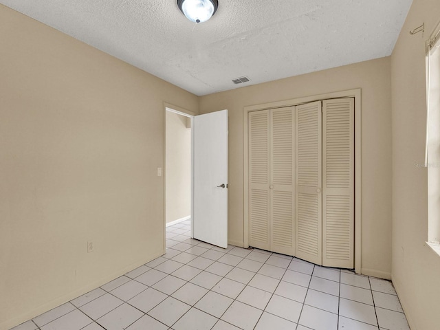 unfurnished bedroom featuring light tile patterned floors, a textured ceiling, and a closet