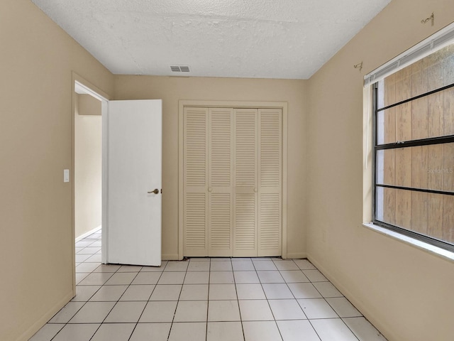 unfurnished bedroom featuring light tile patterned floors, a textured ceiling, and a closet